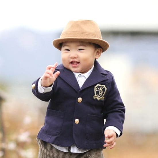 Bébé portant un blazer bleu marine avec écusson, pantalon rayé et chapeau, collection vêtements bébé créateur seconde main Chou de Chic.