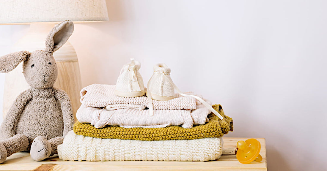 Photo d'une pile de vêtements pour bébé avec une peluche pour illustrer la mode circulaire et la seconde main pour les tout-petits