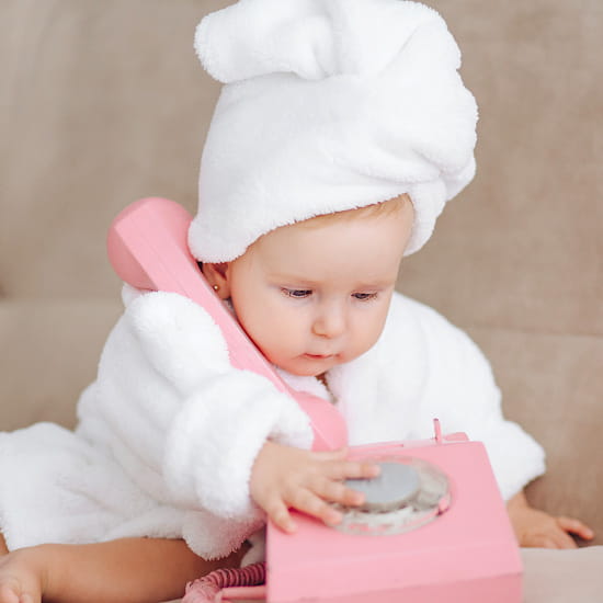 Bébé fille habillé d'un peignoir blanc évoquant le besoin de vêtements bébé d'occasion