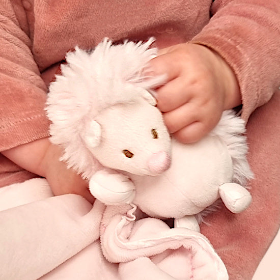 Bébé fille tenant un doudou hérisson rose de marque Tartine et Chocolat dans ses main, cadeau de naissance doux et raffiné