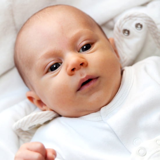 Bébé garçon enveloppé dans un pyjama en coton blanc avec ouverture frontale, cadeau de naissance utile et pratique