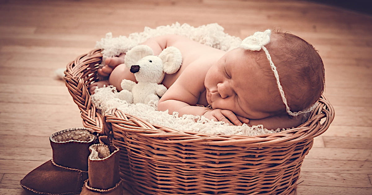 Bébé dormant dans un panier avec un doudou, illustrant l’idée d’habiller les enfants avec des vêtements de seconde main