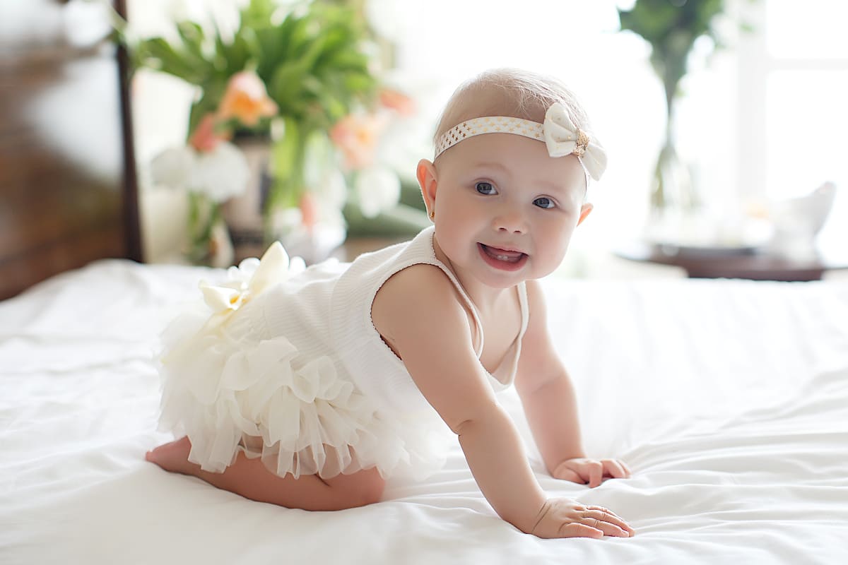 Bébé fille habillée d'une robe écrue décorée de volants et de nœuds